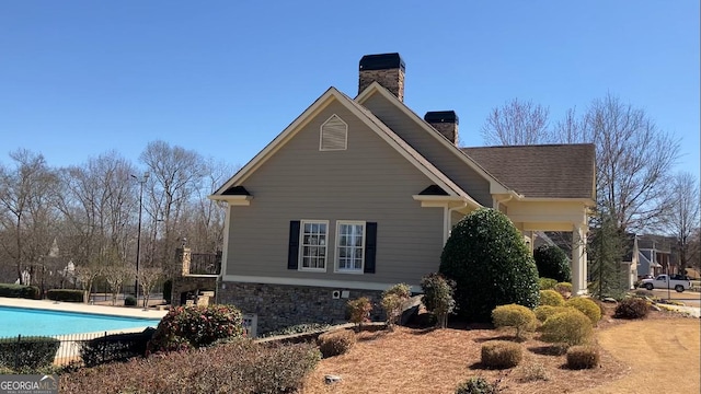 view of side of home with an outdoor pool and a chimney