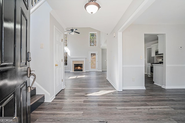 entrance foyer featuring baseboards, stairs, a warm lit fireplace, dark wood-style floors, and a ceiling fan