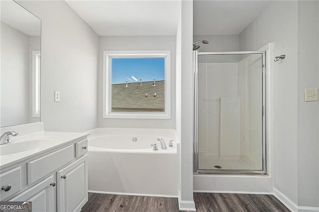 full bath with a stall shower, vanity, a garden tub, and wood finished floors