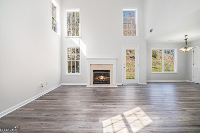 unfurnished living room with baseboards, dark wood finished floors, and a tiled fireplace