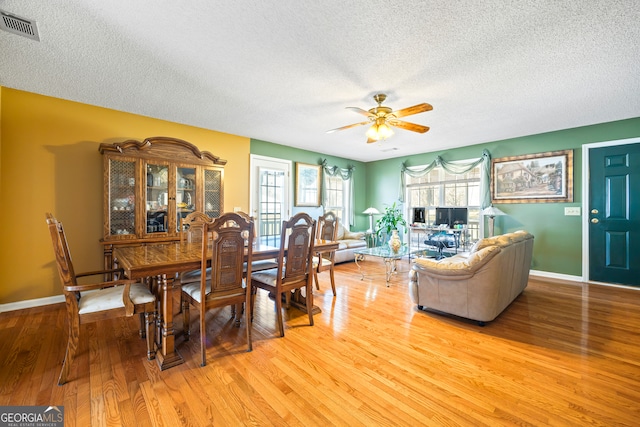 dining area featuring visible vents, a ceiling fan, a textured ceiling, wood finished floors, and baseboards