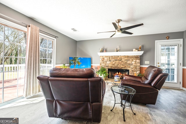 living area with a wealth of natural light, visible vents, a textured ceiling, and a fireplace