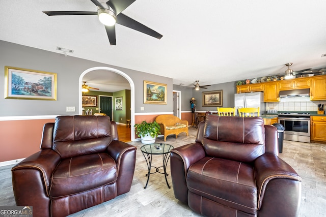 living room featuring a ceiling fan, arched walkways, and visible vents