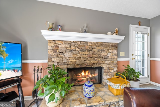 living area featuring a fireplace, a textured ceiling, and baseboards