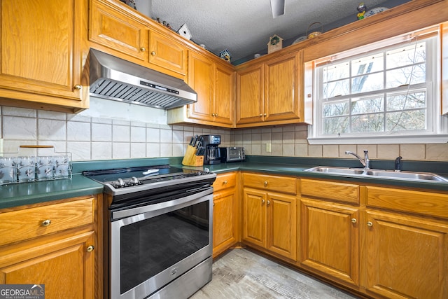 kitchen featuring stainless steel range with electric stovetop, brown cabinetry, under cabinet range hood, and a sink