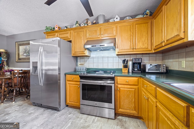 kitchen with extractor fan, dark countertops, light wood-type flooring, and appliances with stainless steel finishes