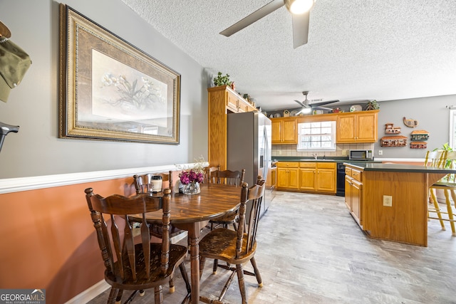 dining area featuring a textured ceiling, light wood-style flooring, and ceiling fan