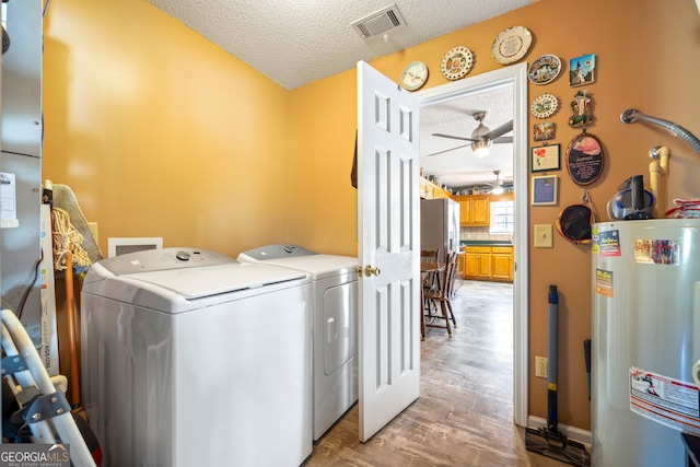 laundry room with washing machine and clothes dryer, visible vents, gas water heater, laundry area, and a textured ceiling