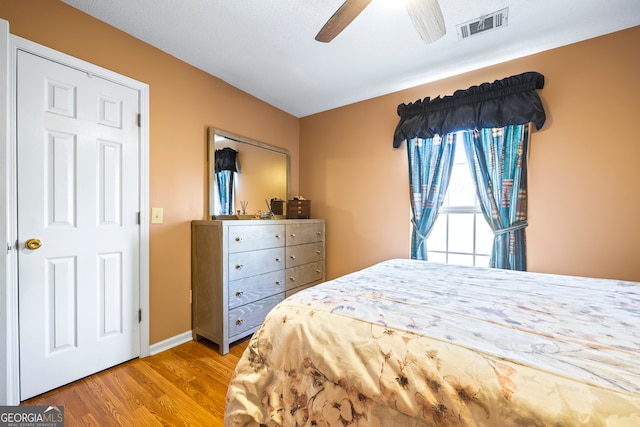 bedroom with visible vents, baseboards, a ceiling fan, and wood finished floors