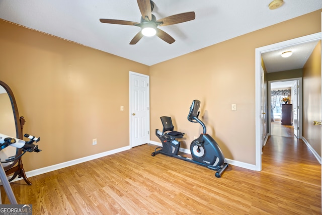 exercise area featuring wood finished floors, baseboards, and ceiling fan