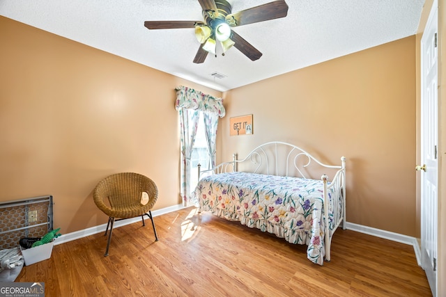 bedroom featuring visible vents, baseboards, a textured ceiling, and wood finished floors