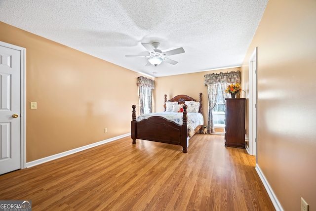 bedroom featuring ceiling fan, baseboards, light wood finished floors, and a textured ceiling