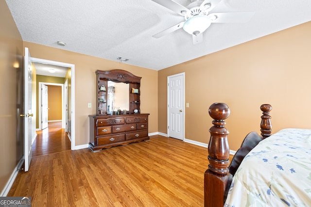 bedroom with visible vents, light wood-style flooring, a textured ceiling, and baseboards