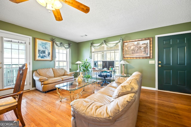 living area featuring a textured ceiling, wood finished floors, visible vents, and baseboards