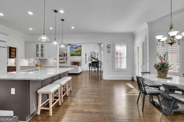 kitchen featuring glass insert cabinets, dark wood finished floors, decorative backsplash, white cabinetry, and a sink