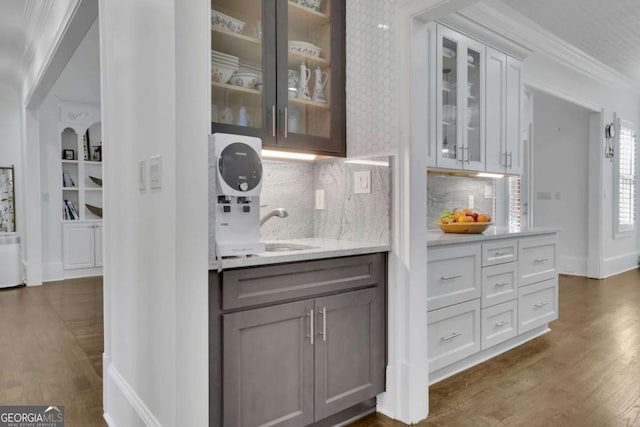 bar featuring tasteful backsplash, crown molding, baseboards, dark wood-style flooring, and a sink