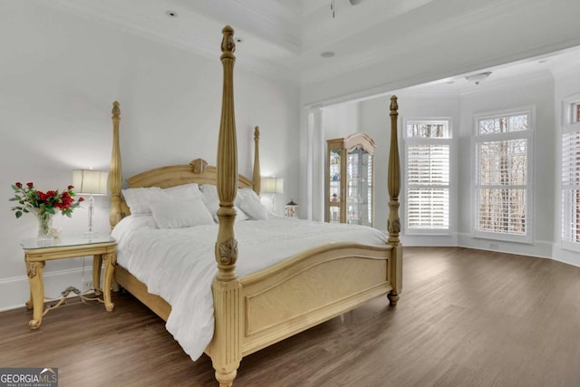 bedroom featuring a ceiling fan, crown molding, wood finished floors, and baseboards