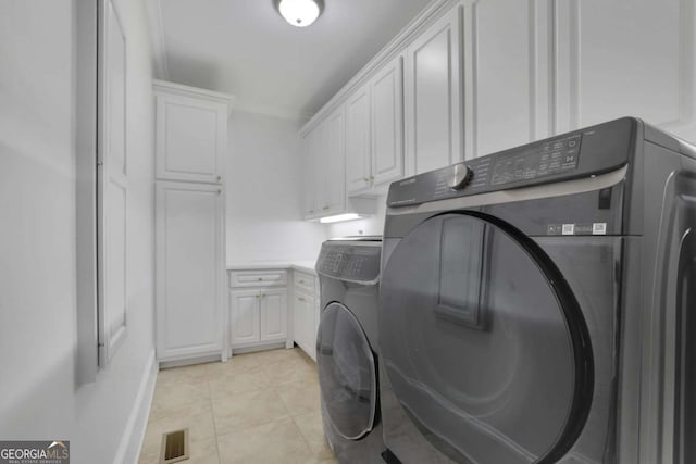 washroom featuring washing machine and dryer, light tile patterned floors, cabinet space, and visible vents