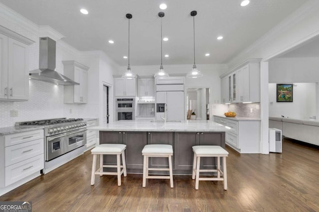 kitchen featuring paneled fridge, a breakfast bar, white cabinetry, double oven, and wall chimney range hood