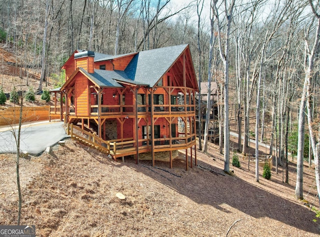 exterior space with a shingled roof and a forest view