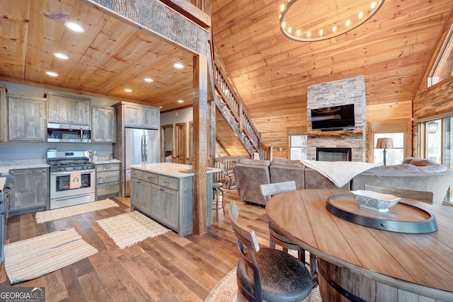 kitchen featuring wood ceiling, light countertops, a stone fireplace, gray cabinets, and stainless steel appliances