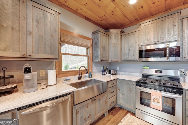 kitchen with a sink, light stone counters, stainless steel appliances, light wood-style floors, and wooden ceiling