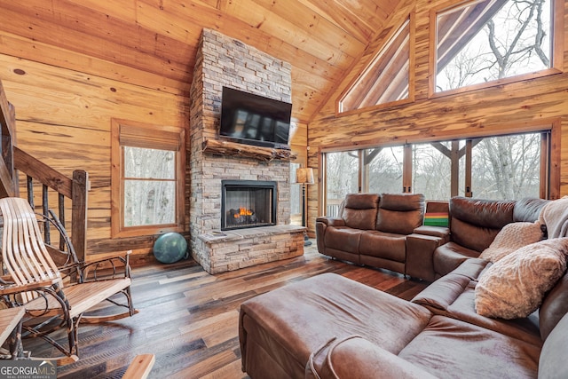 living room featuring a wealth of natural light, a stone fireplace, and wood walls