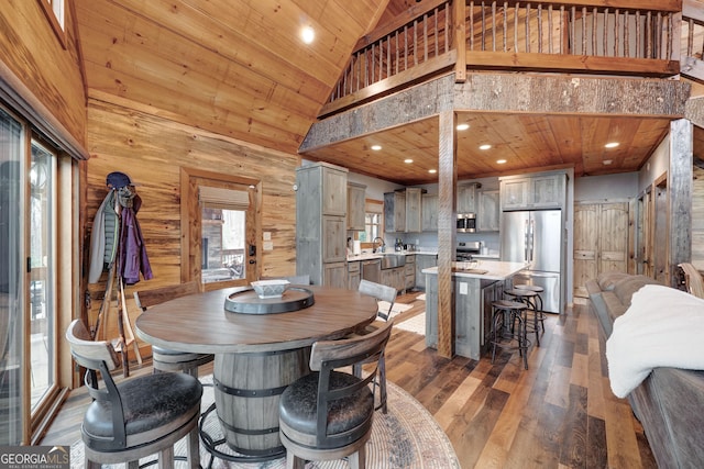 dining space with wood-type flooring, high vaulted ceiling, wood ceiling, and wood walls