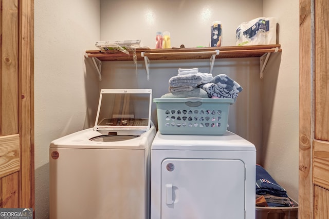 laundry area featuring a textured wall, laundry area, and washer and clothes dryer