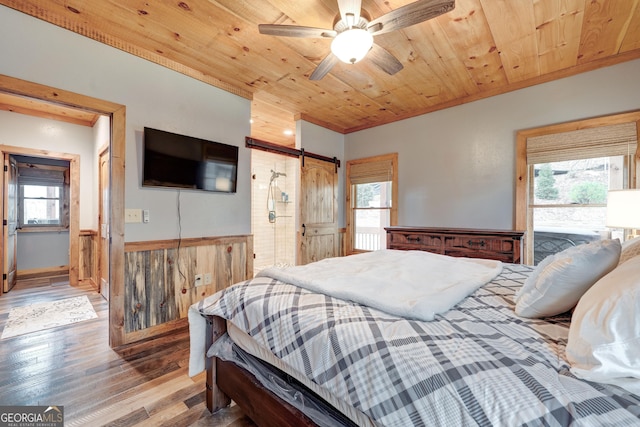 bedroom with light wood finished floors, multiple windows, wooden ceiling, and a barn door