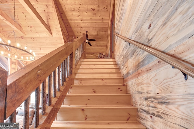 stairway featuring beam ceiling, wooden walls, wood ceiling, and a chandelier