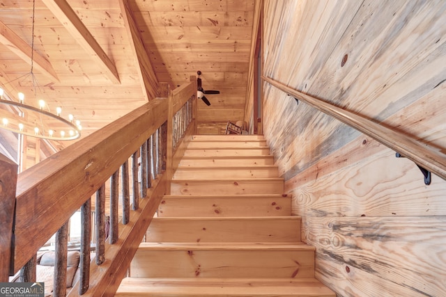 staircase featuring an inviting chandelier, wooden ceiling, beamed ceiling, and wood walls