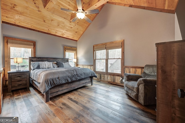 bedroom with a wainscoted wall, multiple windows, wood-type flooring, and wooden ceiling