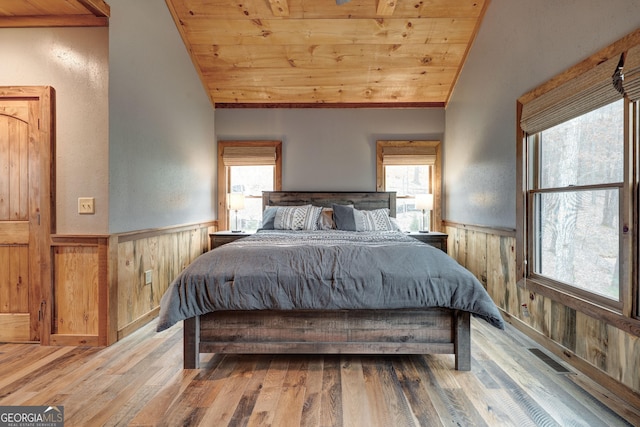 bedroom featuring vaulted ceiling, wood ceiling, a wainscoted wall, and wood walls