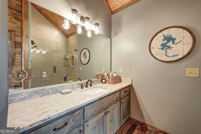bathroom with a shower stall, baseboards, lofted ceiling, wood finished floors, and vanity