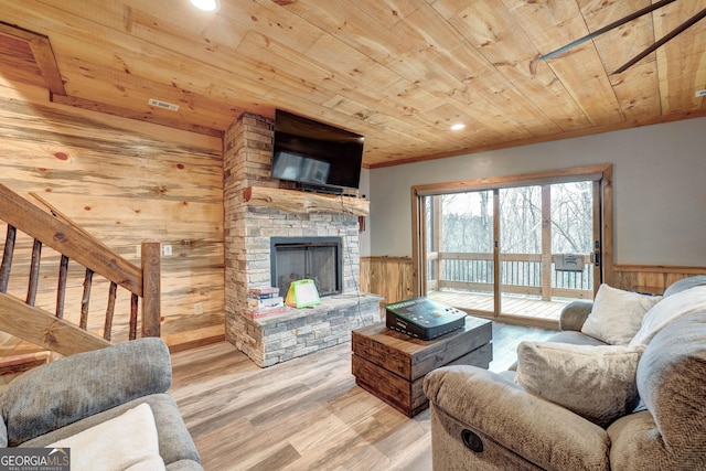 living area featuring wooden ceiling, a fireplace, wood walls, and wainscoting