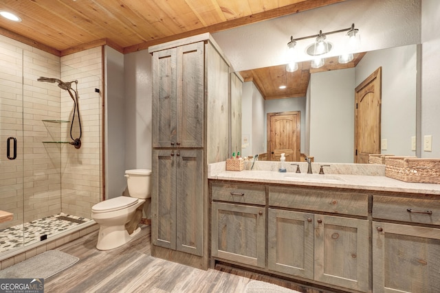 bathroom featuring toilet, wood finished floors, a shower stall, wood ceiling, and vanity