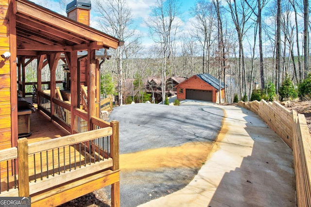 view of yard featuring a forest view, an outdoor structure, and a garage