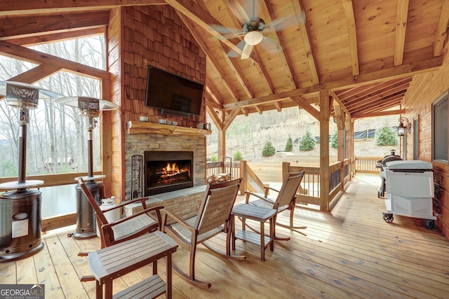 wooden terrace featuring an outdoor stone fireplace and ceiling fan