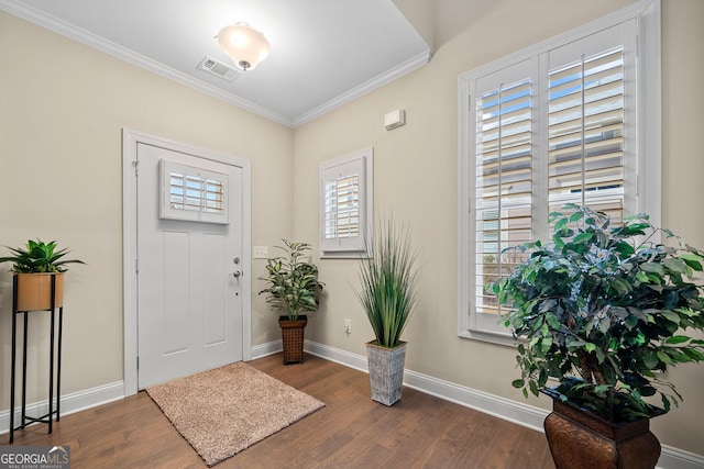 entryway with crown molding, wood finished floors, visible vents, and baseboards