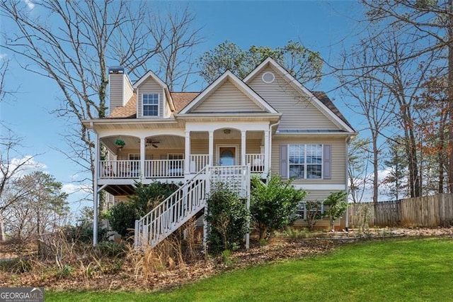 view of front of property with a front lawn, a porch, fence, stairway, and a chimney