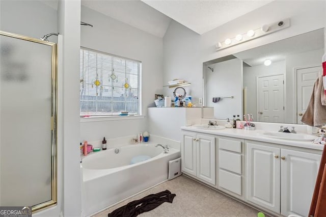 bathroom featuring a bath, a stall shower, double vanity, and a sink