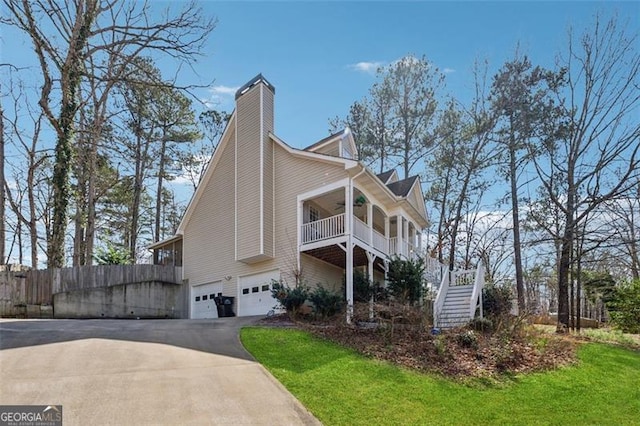 view of home's exterior featuring stairway, fence, ceiling fan, a garage, and aphalt driveway