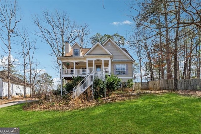 view of front facade with a porch, fence, a front lawn, and a chimney