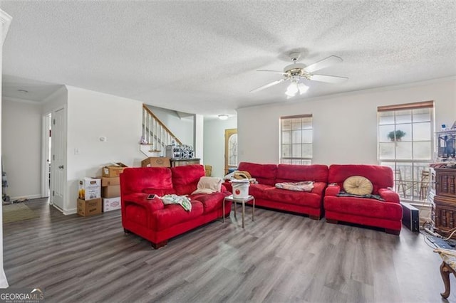 living area featuring crown molding, stairway, wood finished floors, and a healthy amount of sunlight