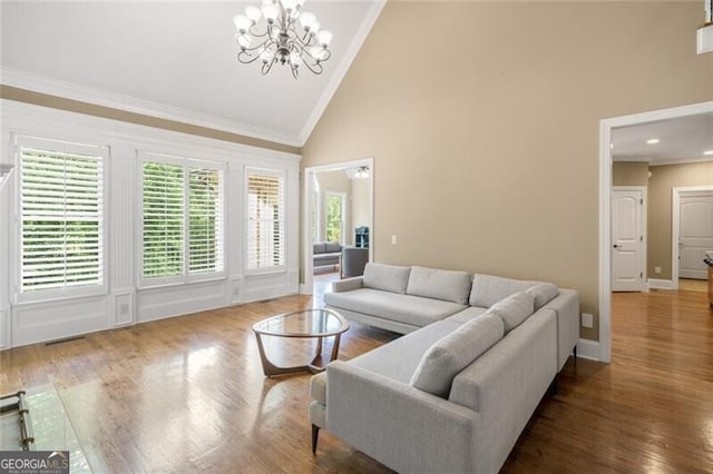 living room featuring visible vents, crown molding, an inviting chandelier, wood finished floors, and high vaulted ceiling