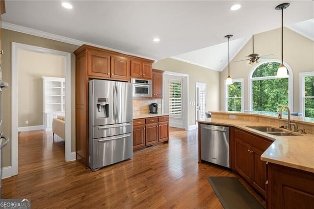 kitchen featuring a sink, tasteful backsplash, appliances with stainless steel finishes, brown cabinetry, and vaulted ceiling