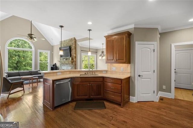 kitchen with a sink, a peninsula, light countertops, and stainless steel dishwasher