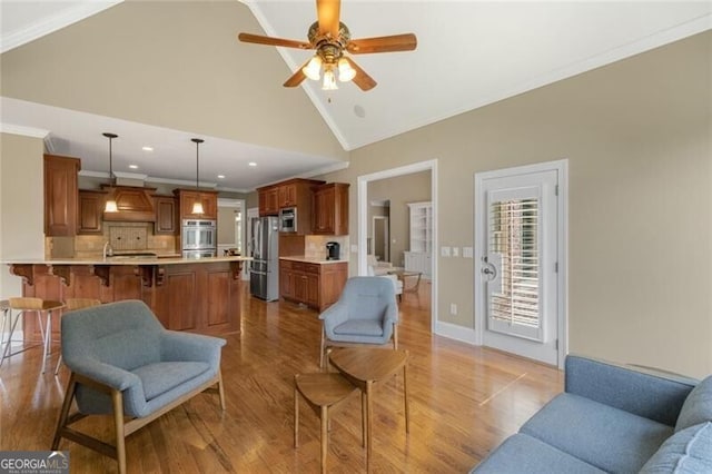 living room featuring wood finished floors, high vaulted ceiling, ornamental molding, and a ceiling fan