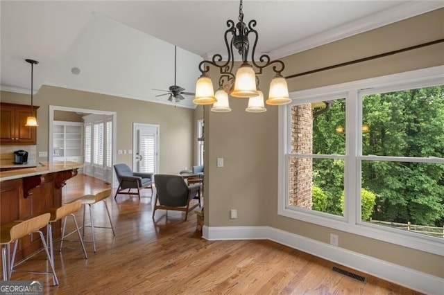 dining room with baseboards, visible vents, crown molding, ceiling fan with notable chandelier, and light wood-type flooring